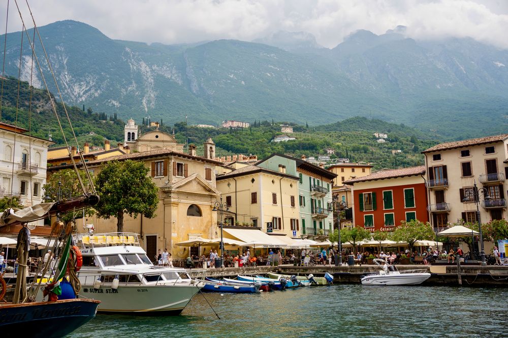 vue sur le port avec les montagnes et les maisons tour du lac de garde italie vespa